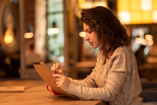 Meisje schrijven nota's in café met een kopje warme koffie en marshmallow — Stockfoto