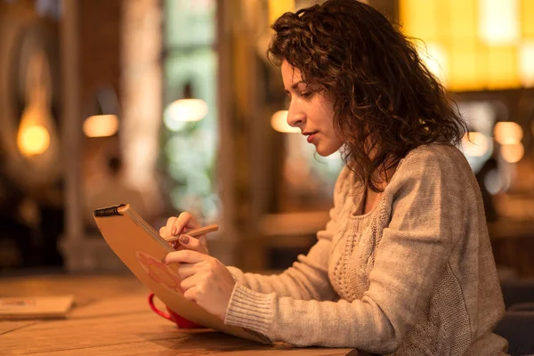 Kız fincan sıcak kahve ve hatmi ile kafede not yazma