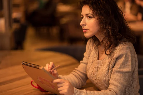 bir fincan sıcak kahve ile bir kafede kız çizer