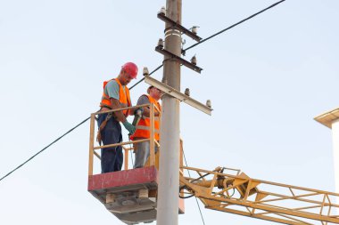 Sütunlardaki elektrikçiler elektrik hattına monte ediyorlar. Profesyonel elektrikçiler kulede çalışıyor. Dnipro / Ukrayna - 08.10.2019