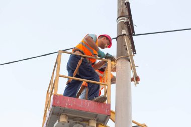 Sütunlardaki elektrikçiler elektrik hattına monte ediyorlar. Profesyonel elektrikçiler kulede çalışıyor. Dnipro / Ukrayna - 08.10.2019