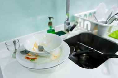 Mutfak lavabosunda bir yığın kirli bulaşık. Evde karışıklık var..