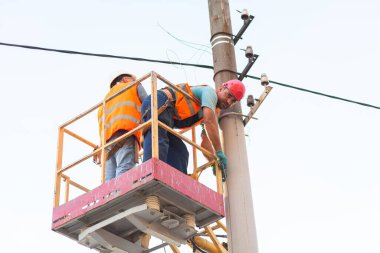 Sütunlardaki elektrikçiler elektrik hattına monte ediyorlar. Profesyonel elektrikçiler kulede çalışıyor. Dnipro / Ukrayna - 08.10.2019