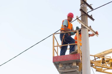 Sütunlardaki elektrikçiler elektrik hattına monte ediyorlar. Profesyonel elektrikçiler kulede çalışıyor. Dnipro / Ukrayna - 08.10.2019