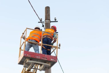 Sütunlardaki elektrikçiler elektrik hattına monte ediyorlar. Profesyonel elektrikçiler kulede çalışıyor. Dnipro / Ukrayna - 08.10.2019