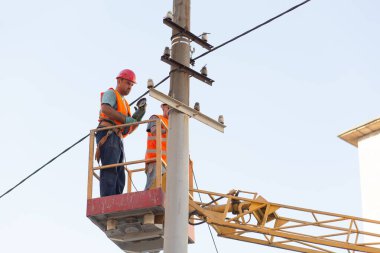 Sütunlardaki elektrikçiler elektrik hattına monte ediyorlar. Profesyonel elektrikçiler kulede çalışıyor. Dnipro / Ukrayna - 08.10.2019