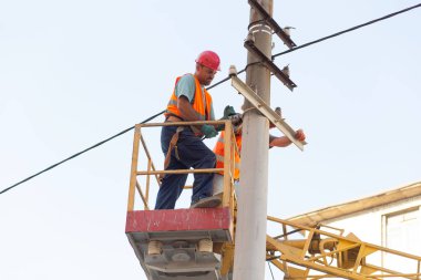 Sütunlardaki elektrikçiler elektrik hattına monte ediyorlar. Profesyonel elektrikçiler kulede çalışıyor. Dnipro / Ukrayna - 08.10.2019