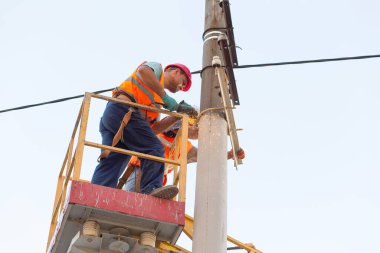 Sütunlardaki elektrikçiler elektrik hattına monte ediyorlar. Profesyonel elektrikçiler kulede çalışıyor. Dnipro / Ukrayna - 08.10.2019