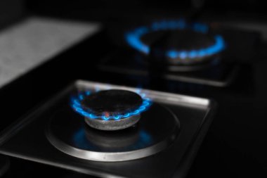 Gaz ocağı, gaz yanıyor. Karanlık bir arkaplanda gaz yakıcı.