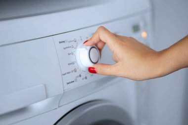 Kız çamaşır makinesi için çamaşır programını hazırlıyor.