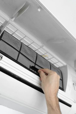 Adam evdeki klimanın filtresini tozdan temizliyor. Çok kirli bir klima filtresi. İklim ekipmanı bakımı