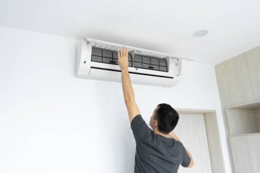Adam evdeki klimanın filtresini tozdan temizliyor. Çok kirli bir klima filtresi. İklim ekipmanı bakımı
