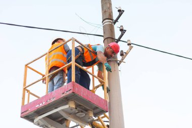 Sütunlardaki elektrikçiler elektrik hattına monte ediyorlar. Profesyonel elektrikçiler kulede çalışıyor. Dnipro / Ukrayna - 08.10.2019