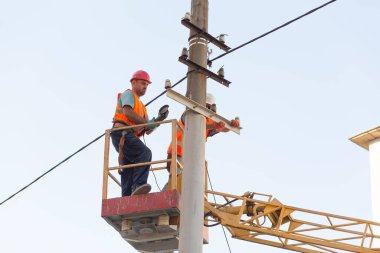 Sütunlardaki elektrikçiler elektrik hattına monte ediyorlar. Profesyonel elektrikçiler kulede çalışıyor. Dnipro / Ukrayna - 08.10.2019