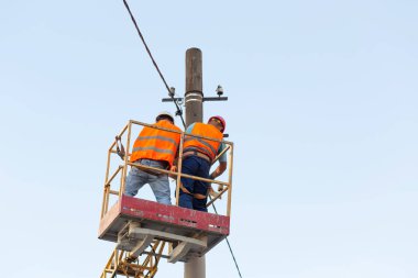 Sütunlardaki elektrikçiler elektrik hattına monte ediyorlar. Profesyonel elektrikçiler kulede çalışıyor. Dnipro / Ukrayna - 08.10.2019
