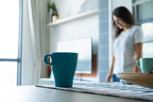 Morning mug of coffee on the table on the background of a girl