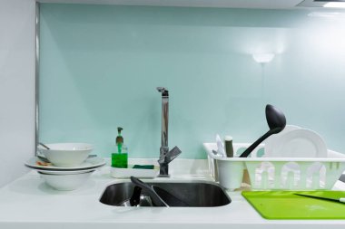 Mutfak lavabosunda bir yığın kirli bulaşık. Evde karışıklık var..