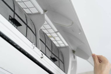 Adam evdeki klimanın filtresini tozdan temizliyor. Çok kirli bir klima filtresi. İklim ekipmanı bakımı