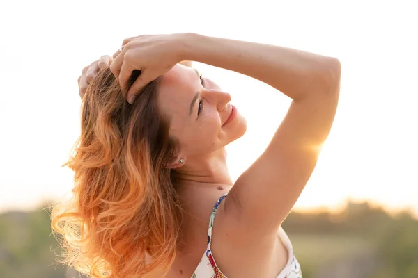 丘のある野原で夕日を楽しむ優しい赤い髪の女の子 — ストック写真