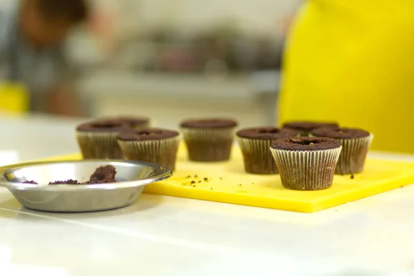 The process of making chocolate cupcakes with sweet cream. Creation of cakes by professional pastry chefs.