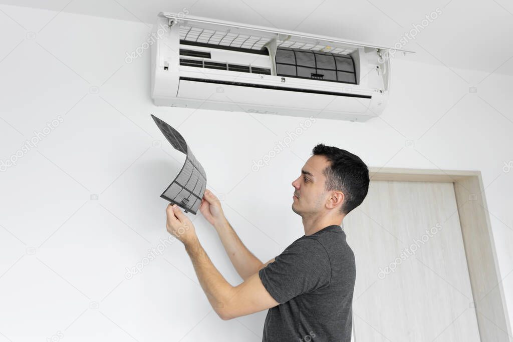 The guy cleans the filter of the home air conditioner from dust. Very dirty air conditioner filter. Climate equipment care