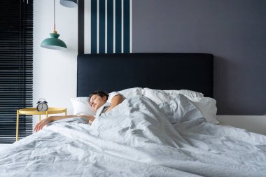 Çalar saatin yanında uyuyan bir kız. Kalkma vakti. Sabah 7 'de. Derin uyku.