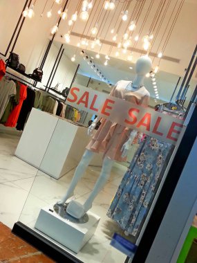 Manken üzerinde bir alışveriş merkezi mağaza Satılık Satılık işareti olan cam arkasında 