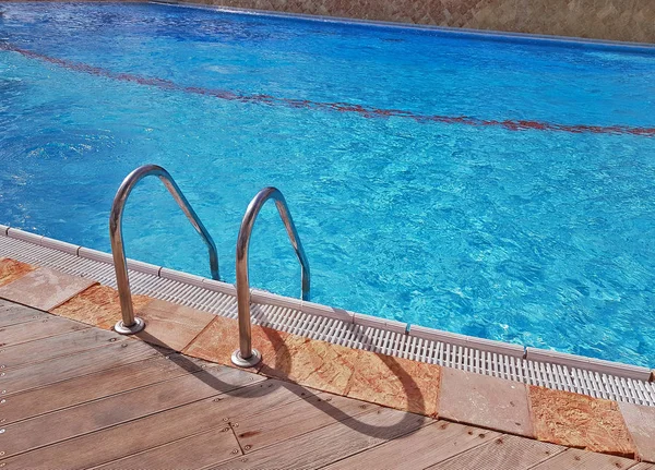 Grab bars ladder in the blue luxury swimming pool. — Stock Photo, Image