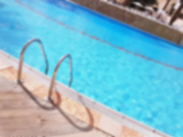 Imagen desenfocada de la escalera de barras de agarre en la piscina de lujo azul. — Foto de Stock
