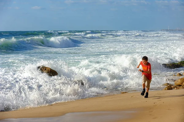 Chłopiec biegnie wzdłuż brzegu — Zdjęcie stockowe