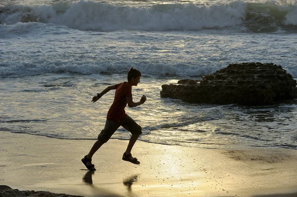Мальчик бежит вдоль берега моря — стоковое фото