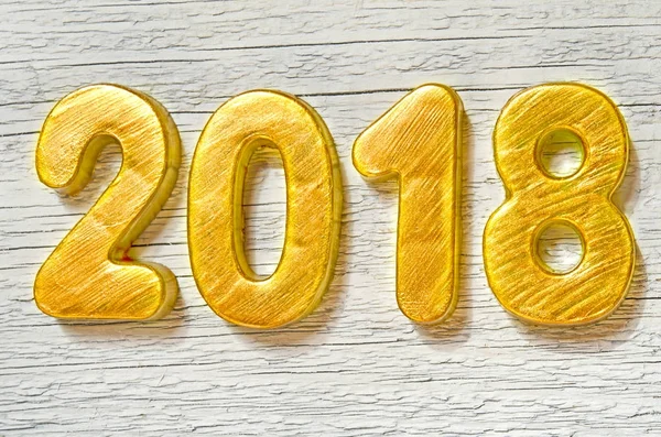 Happy New Year 2018. Golden numbers on white wooden background.