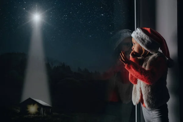 L'enfant regarde par la fenêtre le jour de Noël — Photo