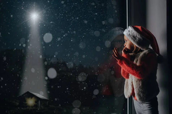 Çocuk pencereden Noel gününde görünüyor. — Stok fotoğraf
