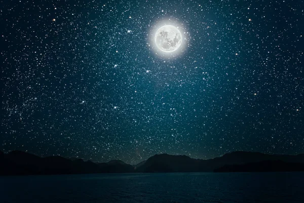 Parlak bir geceye karşı ay. Yıldızlı gökyüzü denize yansıyor. — Stok fotoğraf