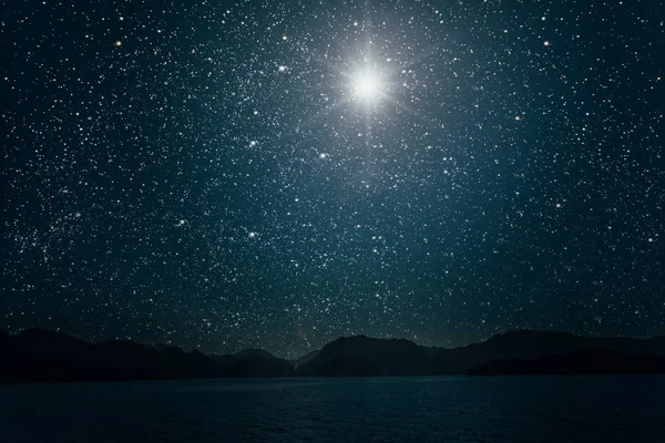 Lune contre une nuit brillante ciel étoilé reflété dans la mer — Photo