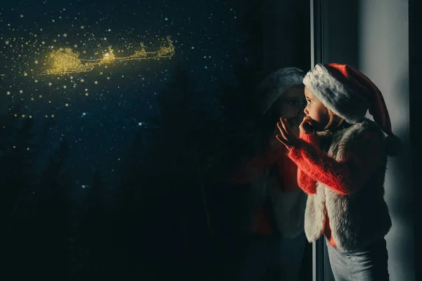 L'enfant regarde par la fenêtre le jour de Noël — Photo