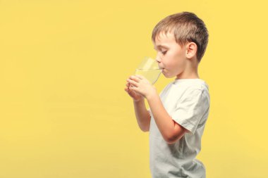 Bir çocuk turkuaz arka planda su içer.