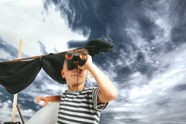 Menino brincando com navio de papelão na parede azul backgr — Fotografia de Stock