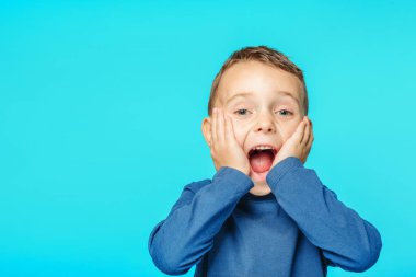 Turkuaz arka planda poz veren örnek bir çocuk