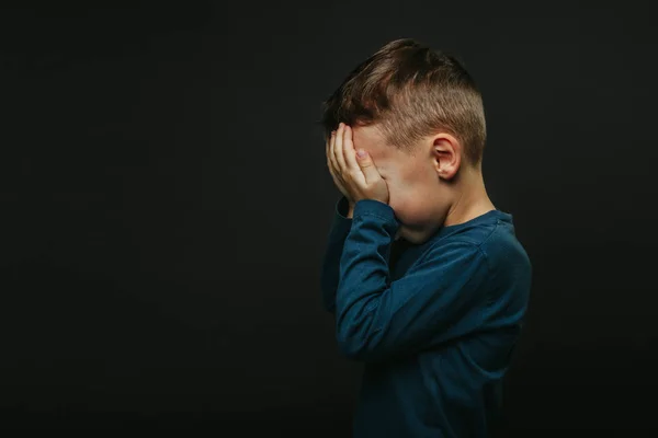 Un bambino la cui depressione è su uno sfondo nero con le mani — Foto Stock