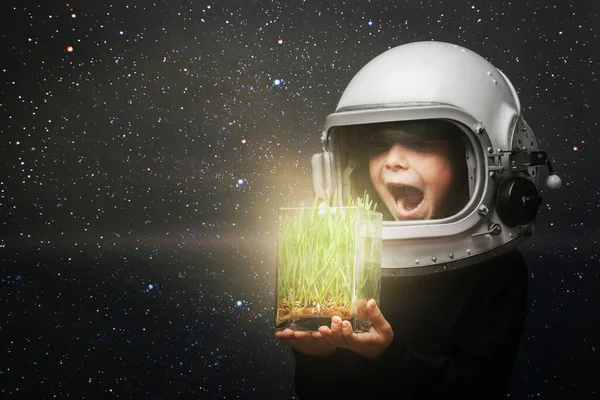 Un niño pequeño sostiene las plantas en un casco de avión. la mirada del niño —  Fotos de Stock