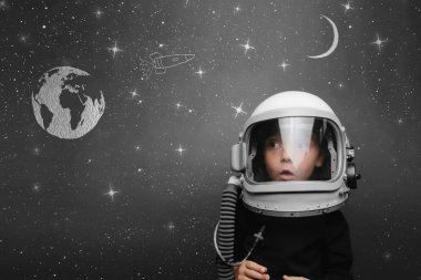 Küçük çocuk astronot kaskı takıp uzayda uçmak istiyor.