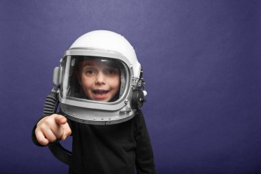 Küçük çocuk Hayalet Mavi arka planda astronot kaskı takarak uzayda uçmak istiyor.