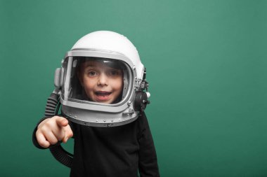 Küçük çocuk Aqua Menthe arka planında astronot kaskı takarak uzayda uçmak istiyor.
