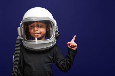  Küçük çocuk Hayalet Mavi arka planda astronot kaskı takarak uzayda uçmak istiyor.