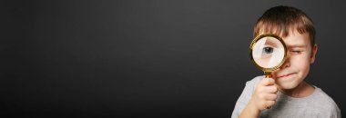 Çocuk, siyah arka plandaki büyüteçten bakıyor. Büyük çocuk gözü.