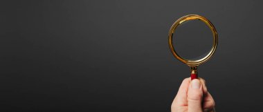 Siyah arka planda büyüteç tutan bir adam var.