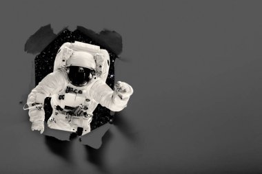 Astronot kağıdı delip uzayda dünyanın üzerinde uçar. Bu görüntünün elementleri NASA tarafından desteklenmektedir