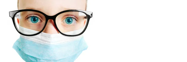 Face of a mask-wearing boy with fear in the eye Close-up on a white background